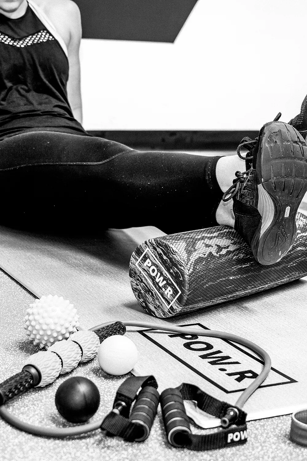 Person using a foam roller behind an assortment of resistance training products